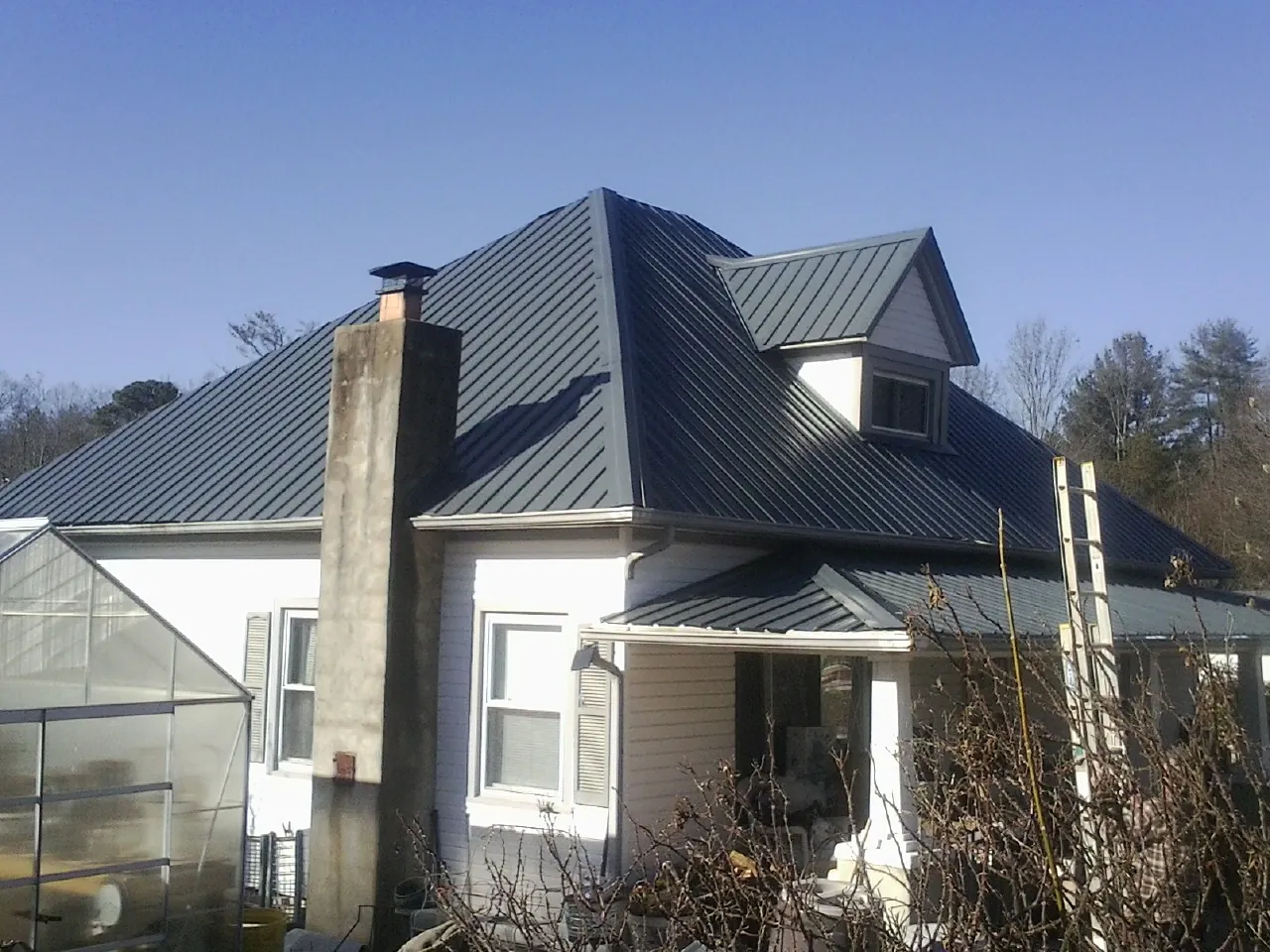 Dark blue standing seam metal roof on a white farmhouse with dormer — Slate & Tile Roof Repair by Roofing Brothers in Hyannis Port