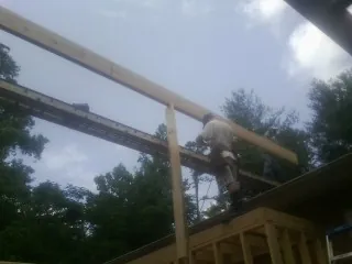 Carpenter setting a ridge beam over a new addition frame — Ice Dam Removal by Roofing Brothers in Hyannis Port