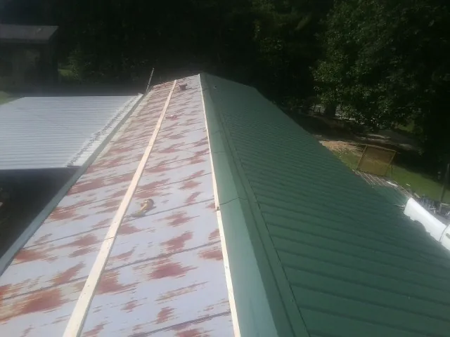 Old rusted panels beside newly installed green metal roofing — Wind Damage Roof Repair by Roofing Brothers in Hyannis Port