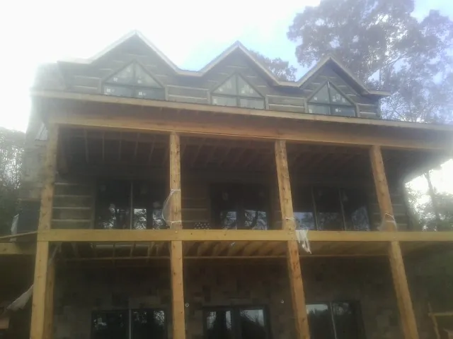 Dormers and porch framing on a large log home under construction — Roof Coating work by our crew in Hyannis Port