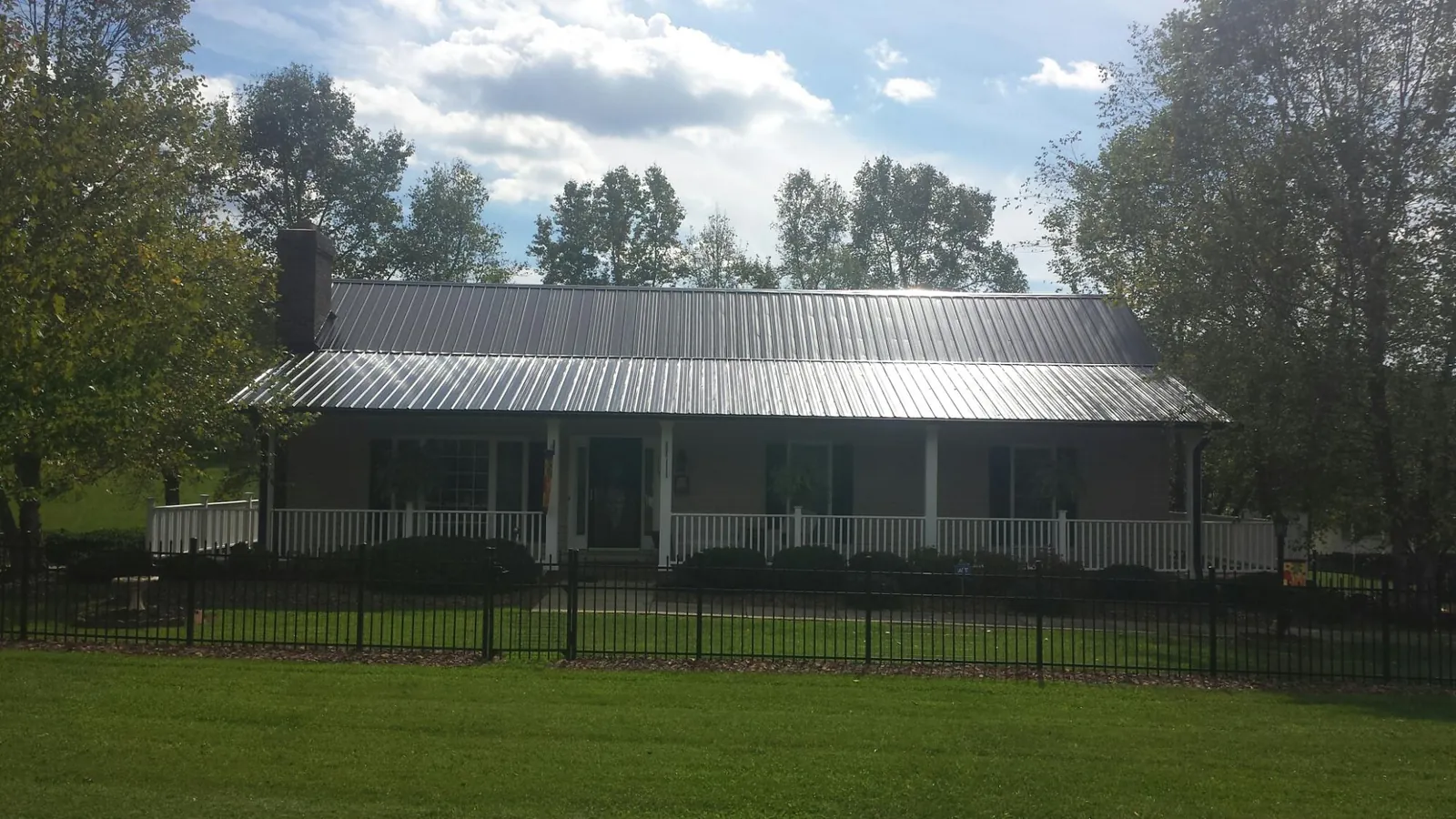 Gray metal roof on a brick ranch with a full width front porch — Gutter Guard Installation work by our crew in Hyannis Port