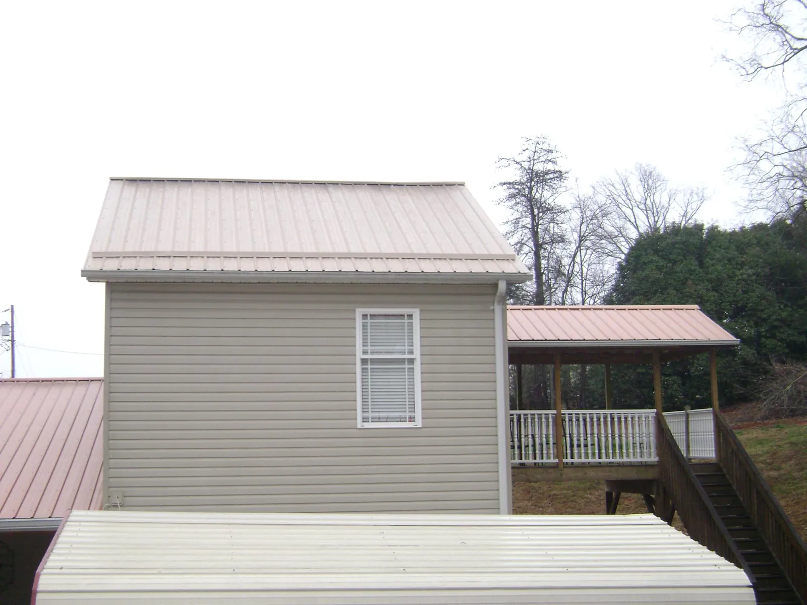 Tan metal roofs on a two story addition and attached porch, from a Roof Replacement job in Hyannis Port