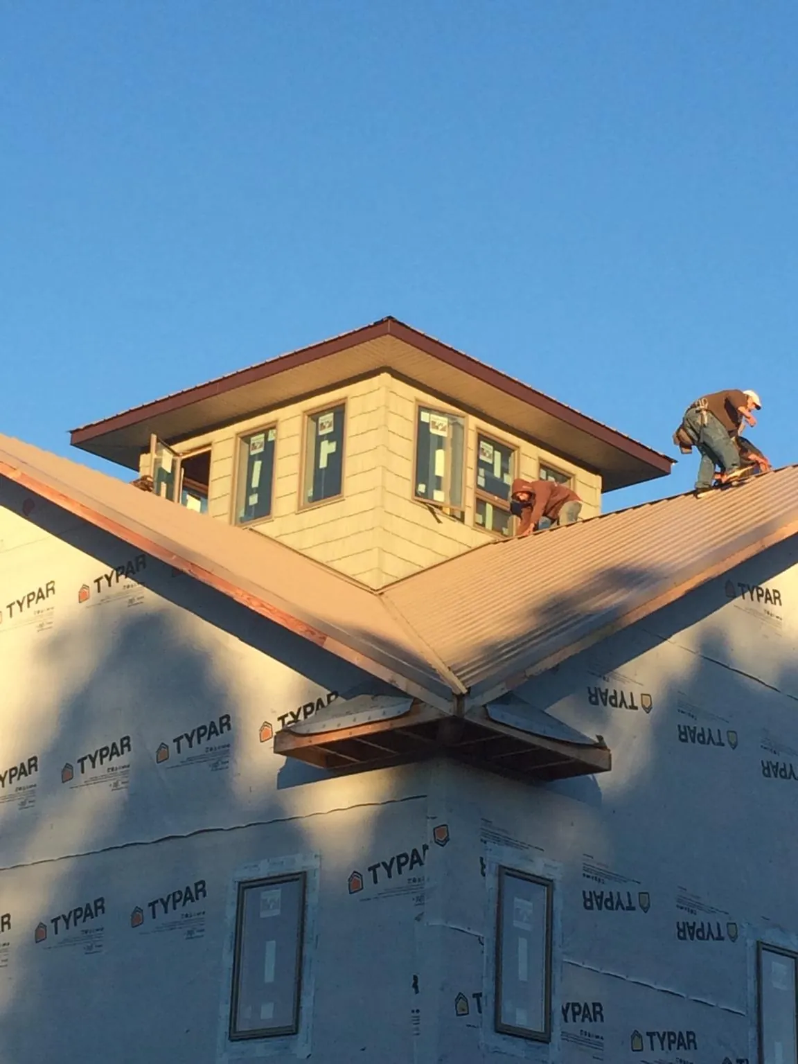 Roofers working around a rooftop cupola on a new metal roof at sunset — Roof Waterproofing in Hyannis Port by Roofing Brothers